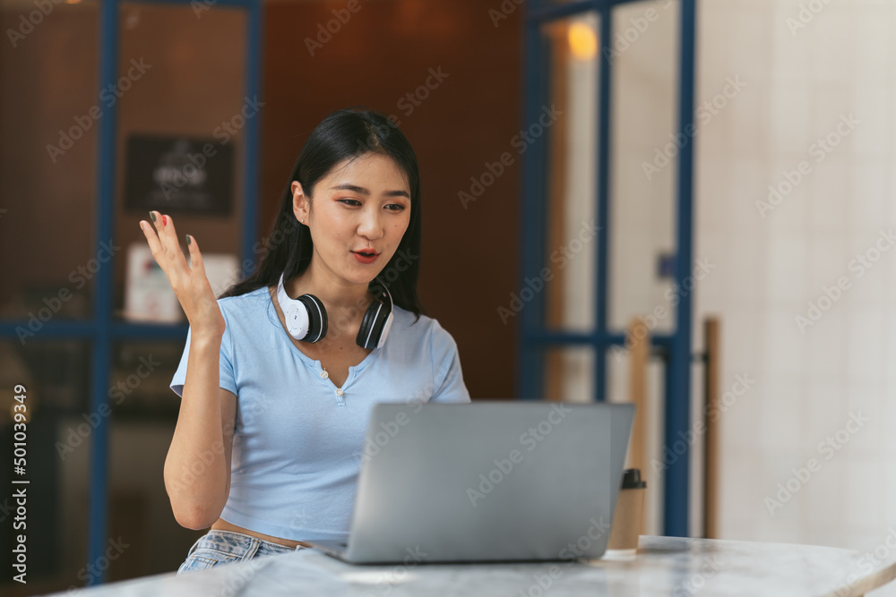 一名亚洲女子在家里的电脑上进行视频通话。一个微笑的女孩在网上和老师一起学习。