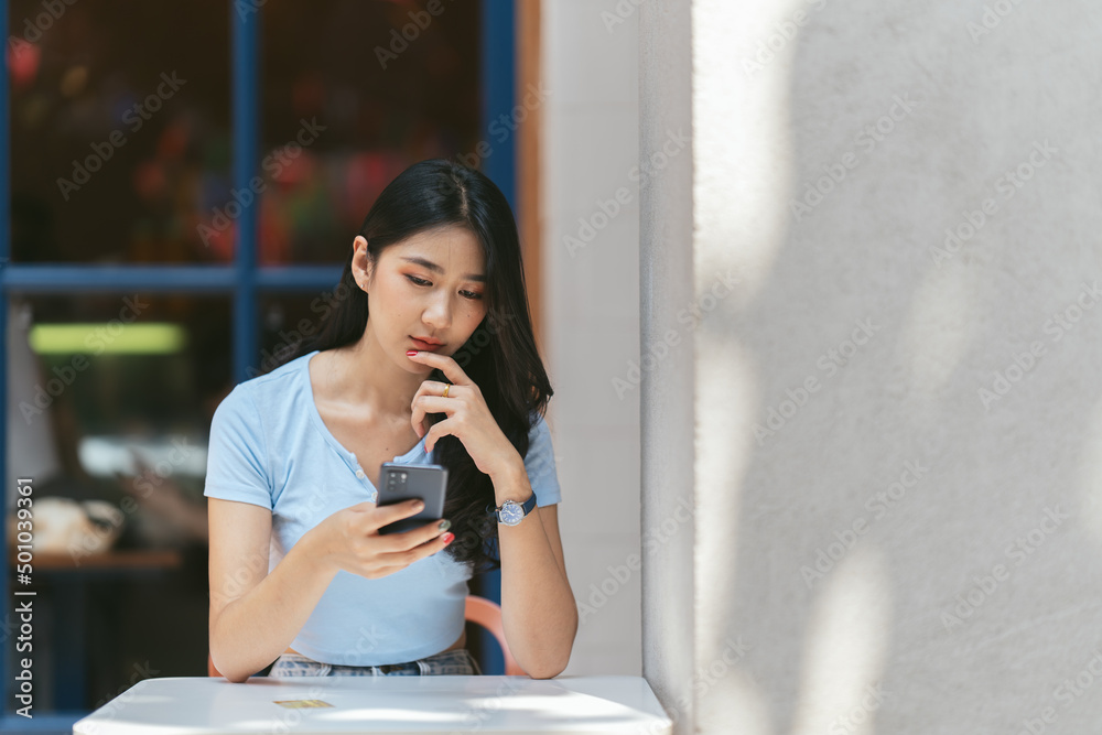 年轻的亚洲女人在咖啡店打电话，开心地笑着。