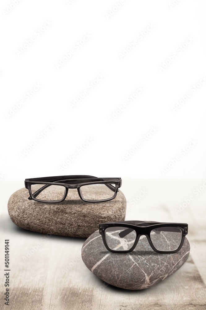 Black glasses on stack stones on gray background. Optic store discount