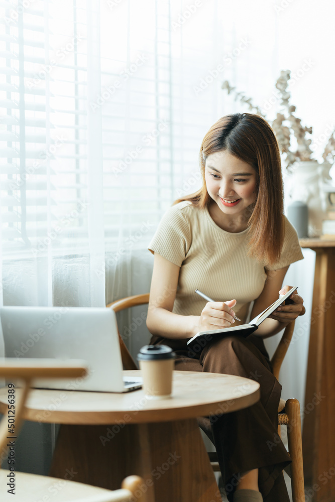 亚洲年轻女性在办公室使用笔记本电脑和财务报告的肖像。