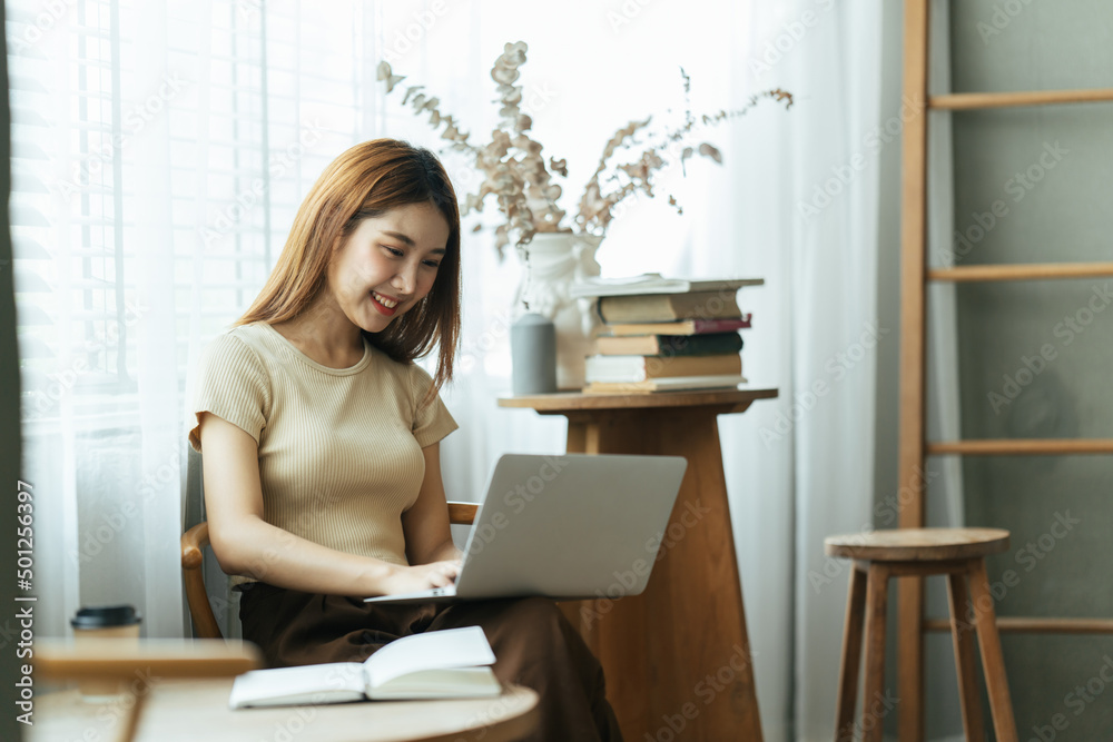 亚洲年轻女性在咖啡馆用笔记本电脑和财务报告工作的肖像。