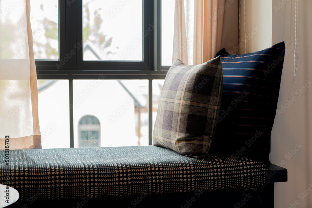 Close-up of beige earth tone pillow cushion set arrange on window bench booth in living room interio