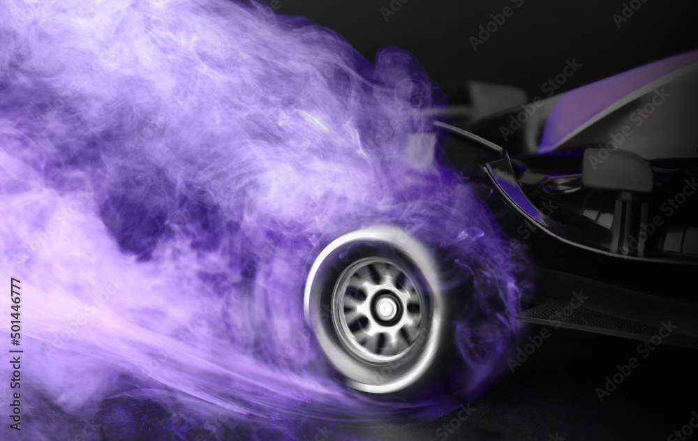 Modern racing car with violet smoke from under wheels on black background, closeup