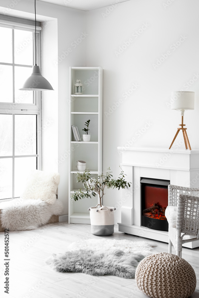 Stylish interior of light room with fireplace and shelf unit near white wall