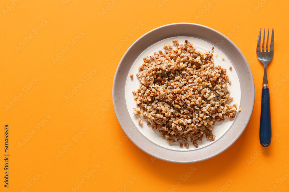 Plate of tasty buckwheat porridge on orange background