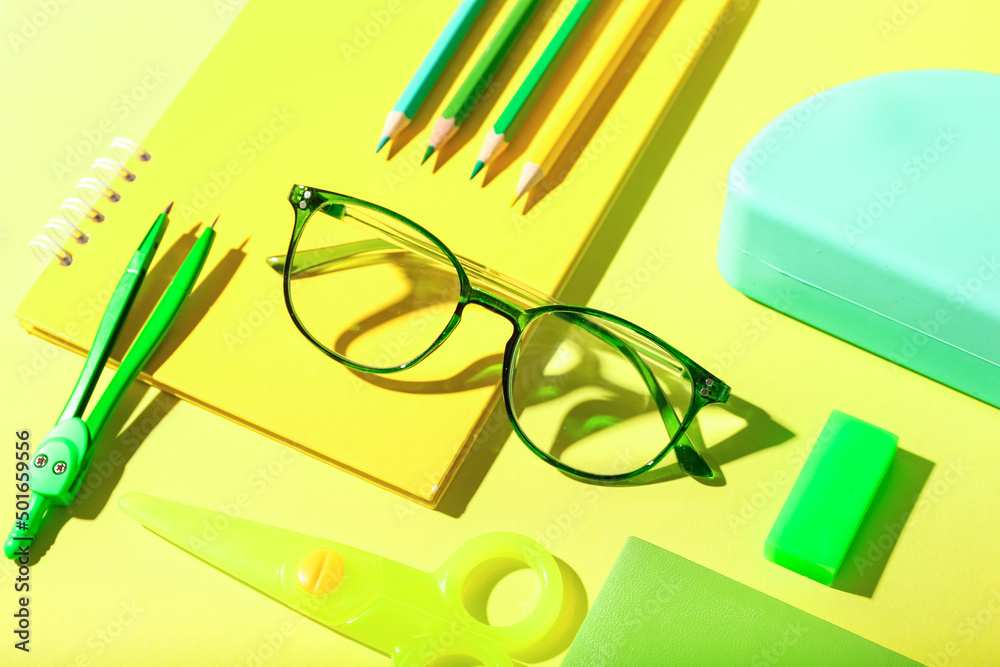 Stylish eyeglasses and stationery on yellow background