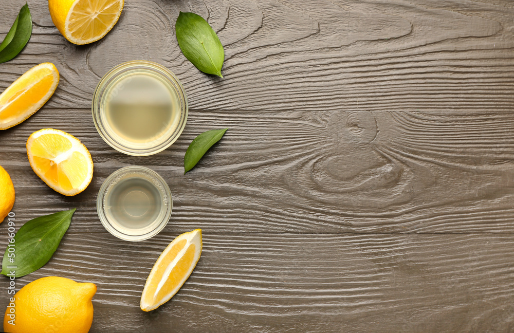 Composition with ripe lemons, bowls of juice and leaves on wooden background