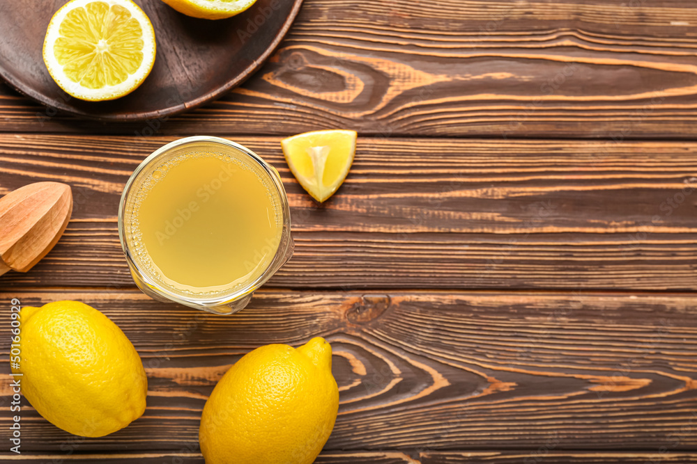 Composition with ripe lemons and glass of juice on wooden background