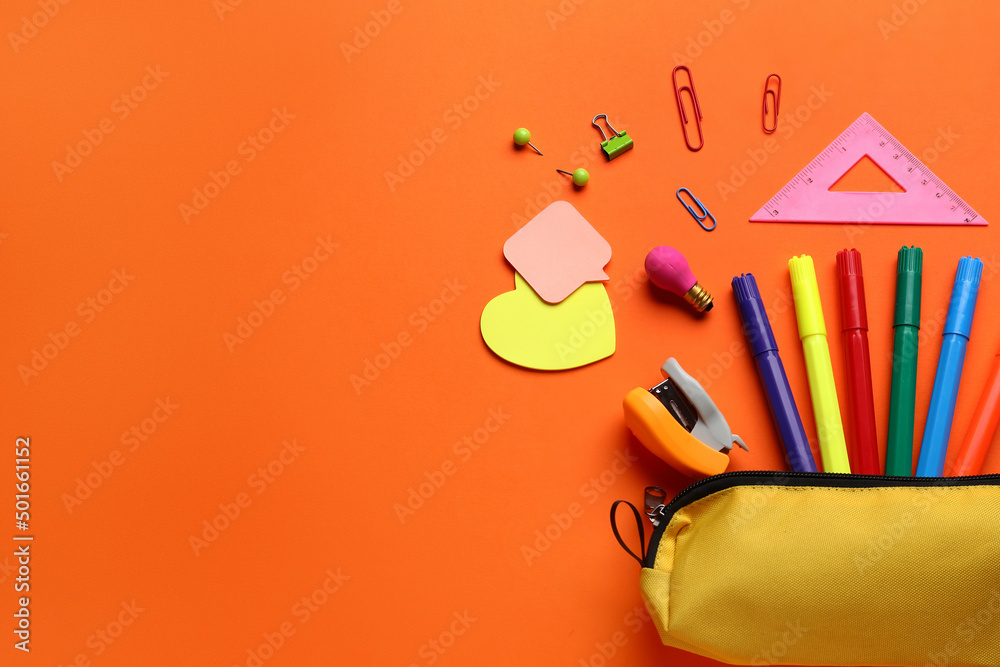 Pencil case with school stationery on orange background, top view