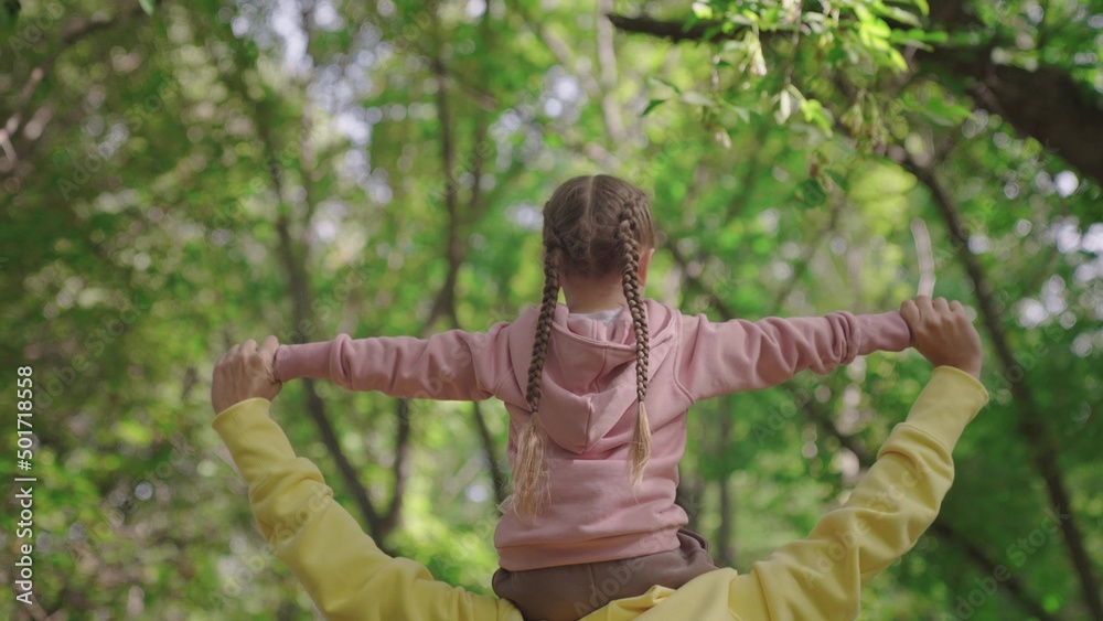 Mom kid walk in woods. Mom walks with her child, kid, daughter on her shoulders in park in spring. H