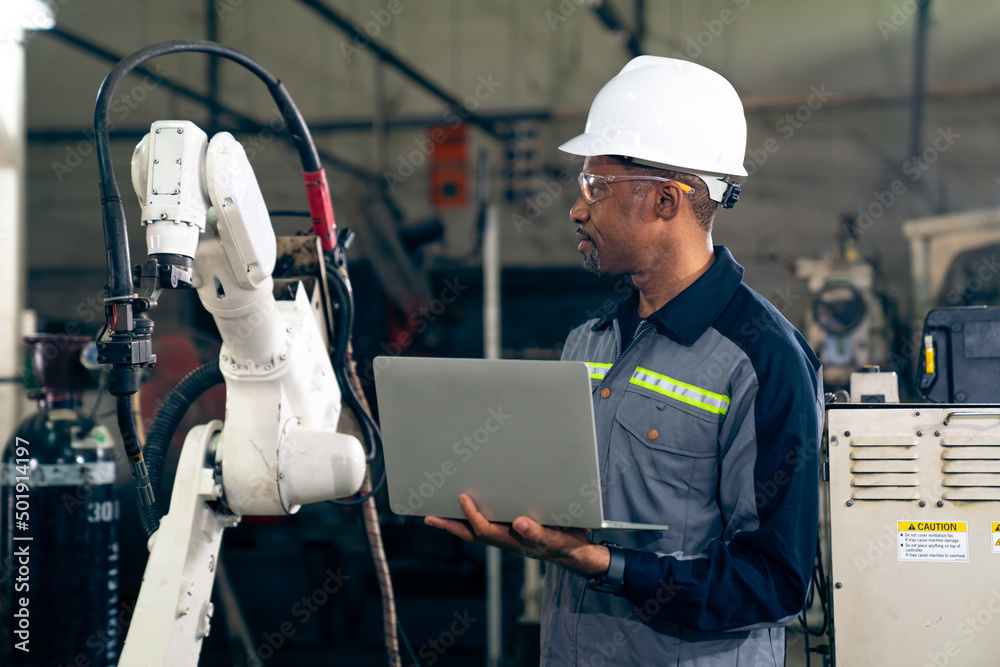 African American factory worker working with adept robotic arm in a workshop . Industry robot progra