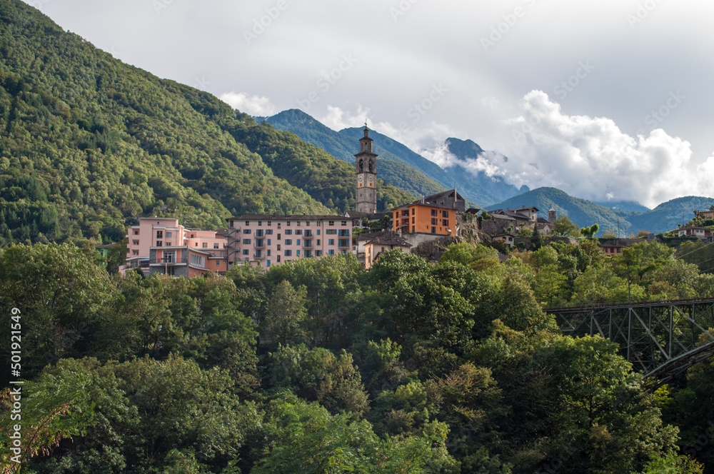 A small village in the Swiss mountains with an iron railway bridge over the valley.