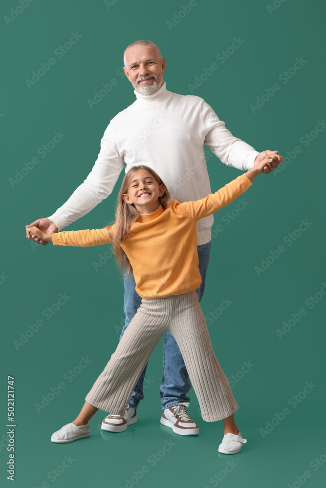 Little girl with her grandfather holding hands on green background