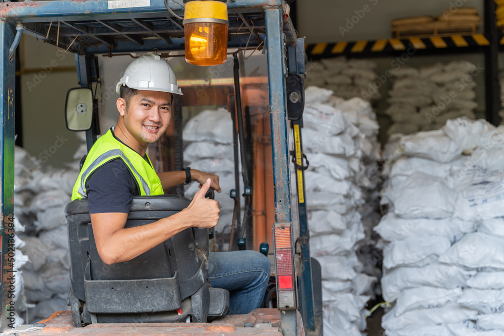 A Worker driving a forklift in alum or chemical warehouse.