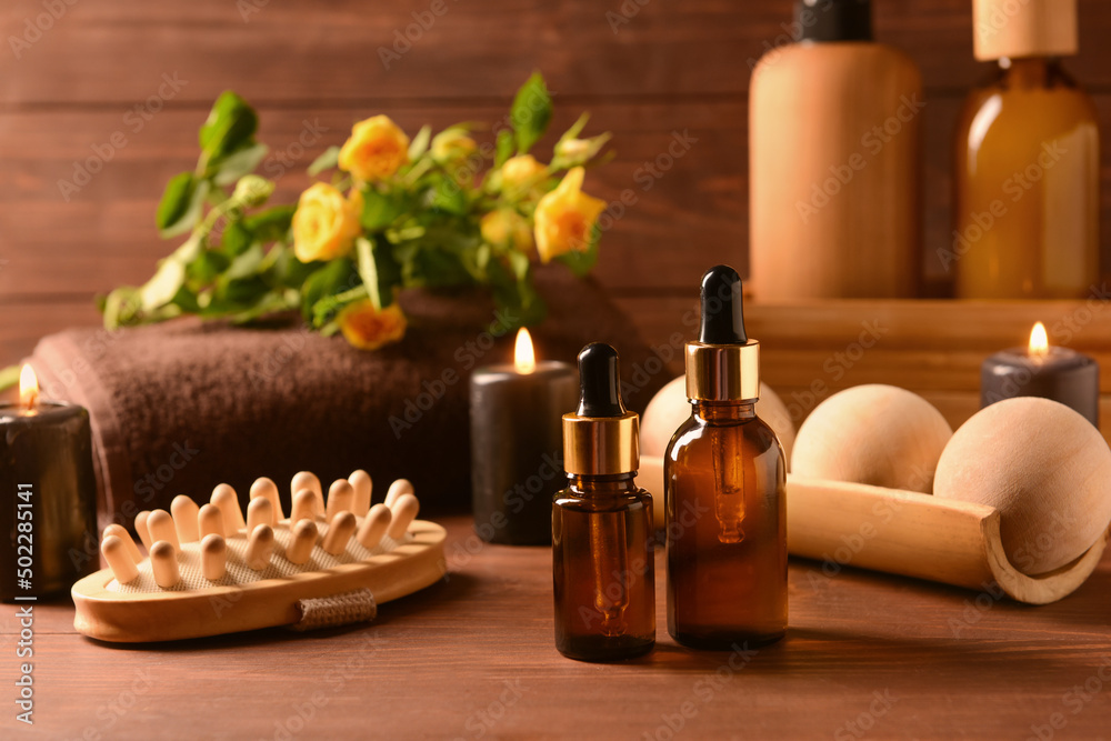 Bottles of essential oil and spa accessories on wooden table