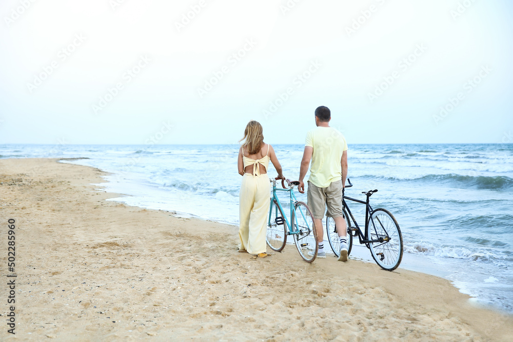 夏日，一对骑着自行车在海边散步的成熟情侣