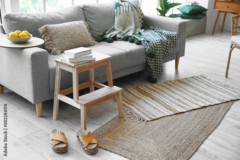 Wooden step ladder with sofa, books and female shoes in interior of living room