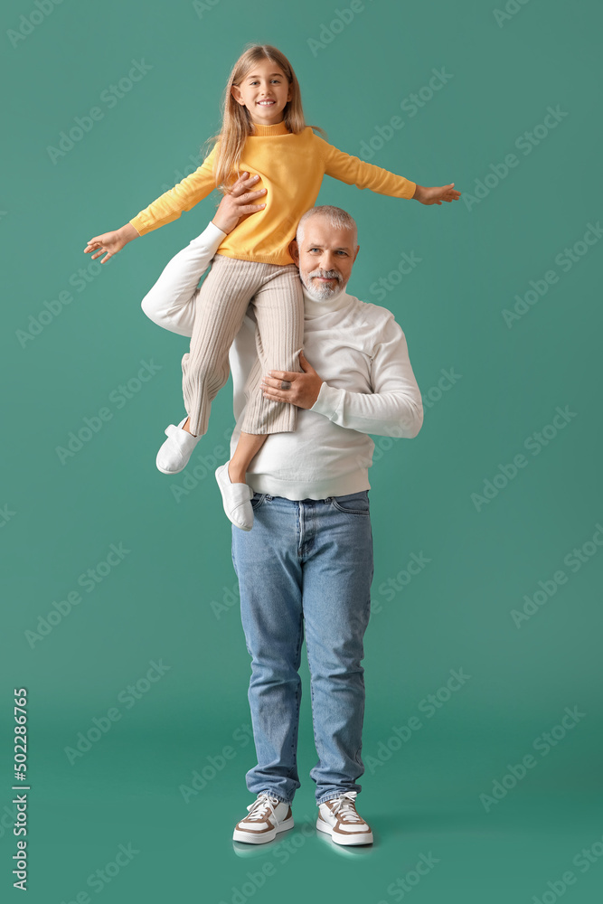 Little girl with her grandfather on green background