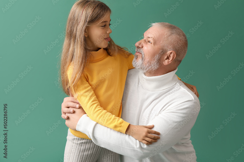 Little girl with her grandfather hugging on green background