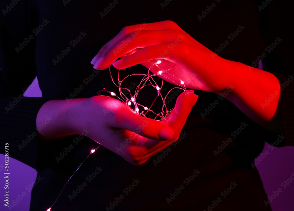 Woman with glowing lights on dark color background, closeup