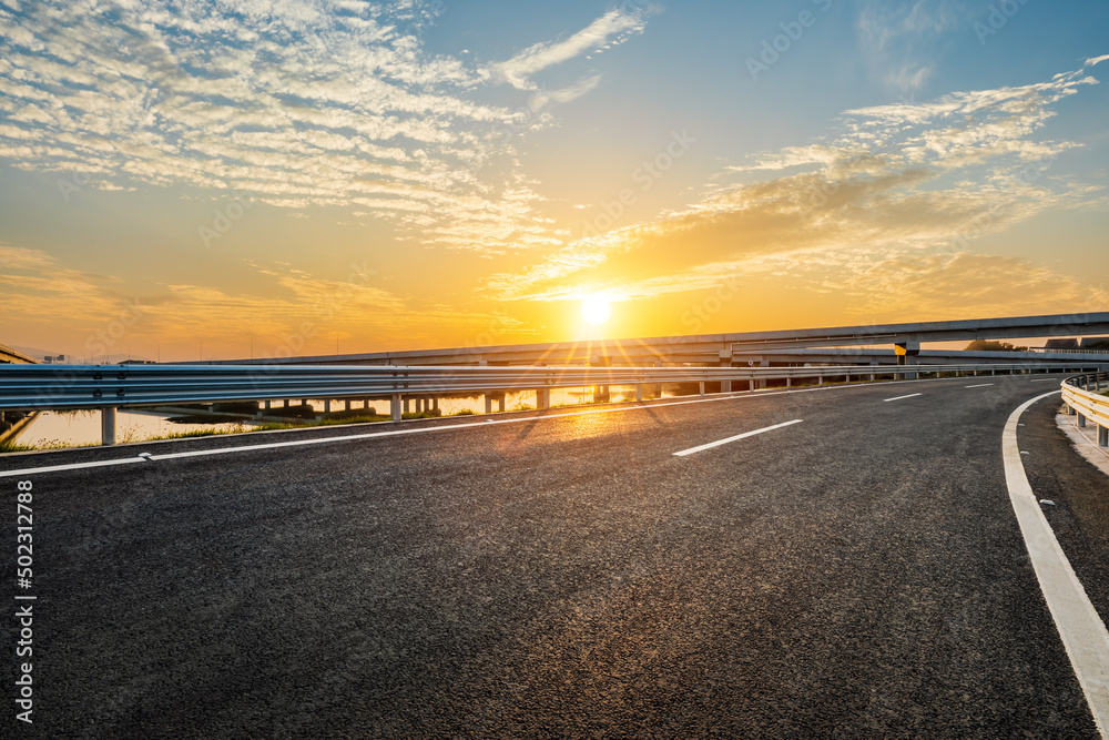 日出时空旷的柏油路和天空的云朵。道路和天空的背景。