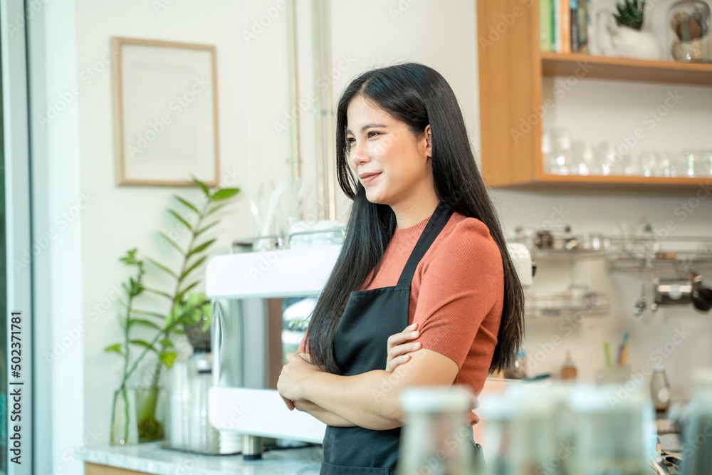 Portrait of smiling baristas with arms crossed at the coffee shop.