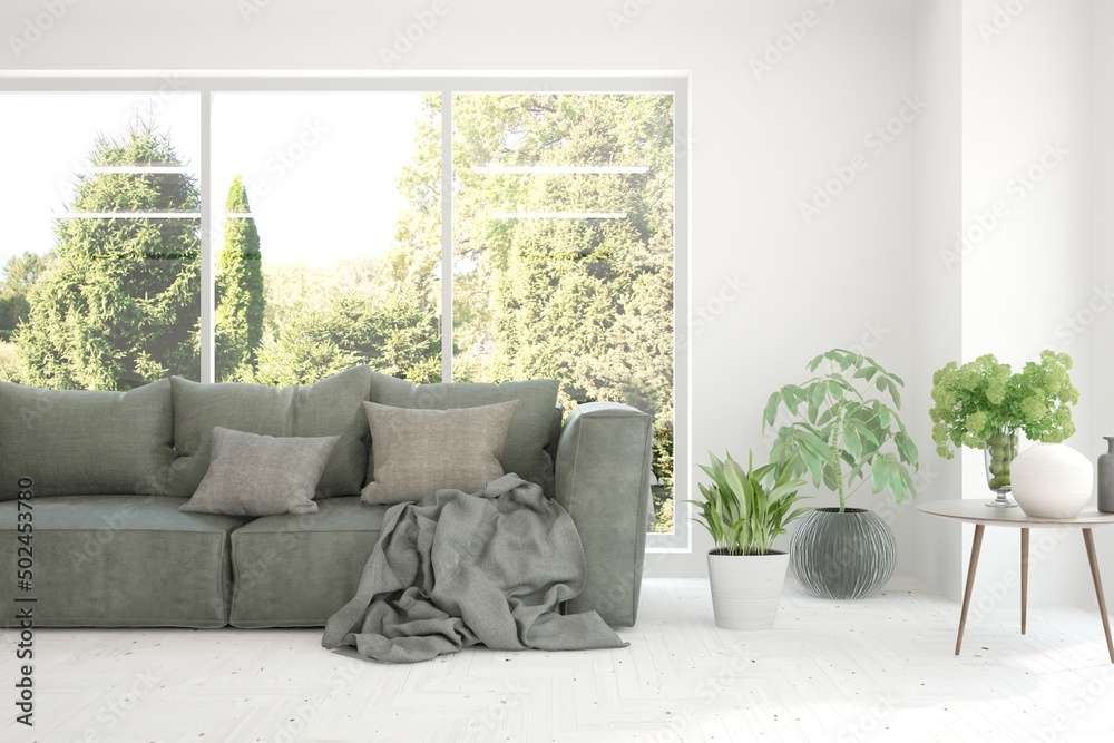 Minimalist living room in white color with sofa and summer landscape in window. Scandinavian interio