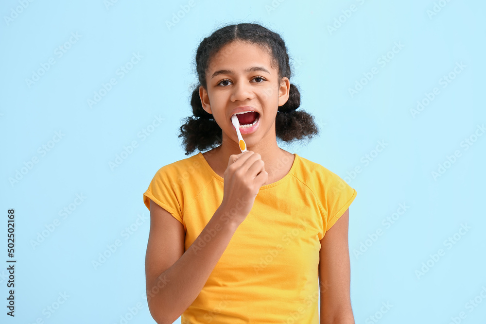 African-American teenage girl brushing teeth on blue background