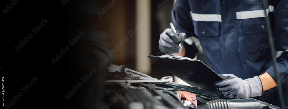 Car service, repair, maintenance concept,auto mechanic man or Smith writing to the clipboard at work