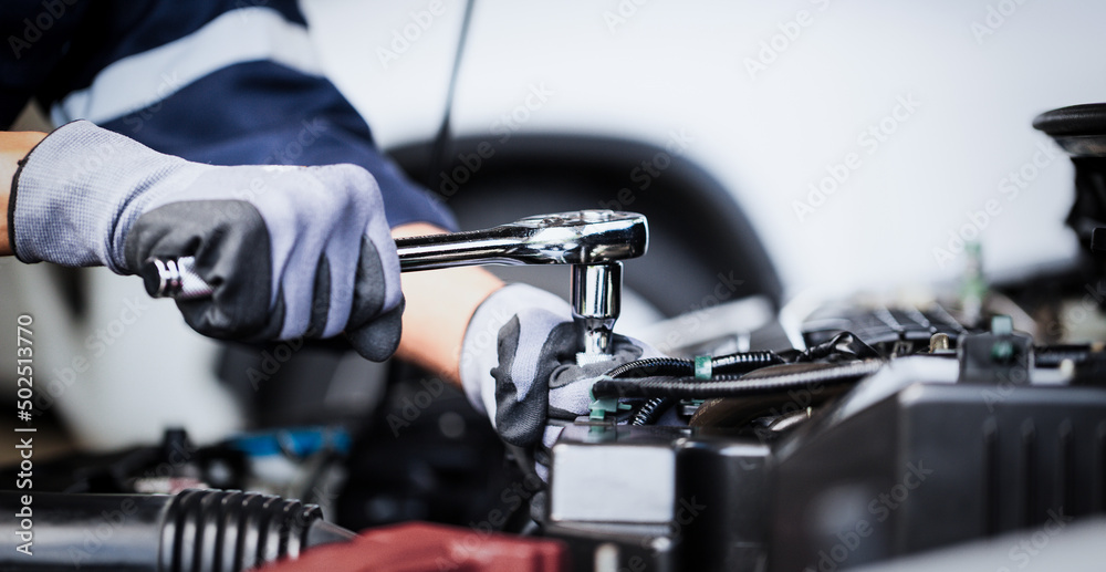 Professional mechanic working on the engine of the car in the garage. Car repair service.