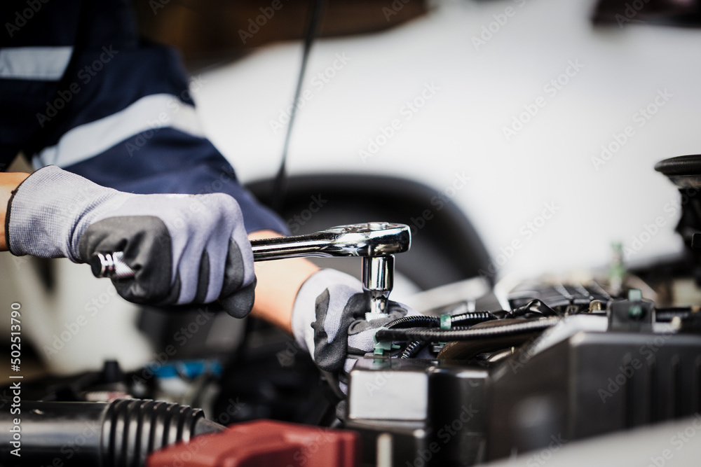 Professional mechanic working on the engine of the car in the garage. Car repair service.