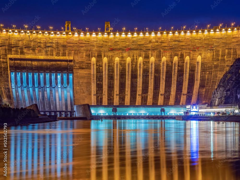 Night picture of 800 fts arched concrete dam of hydroelectric power station. Reflecting lights in th