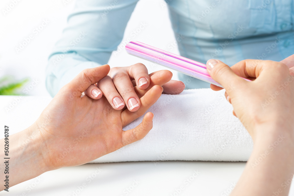 Manicurist using nail file and create clean shape