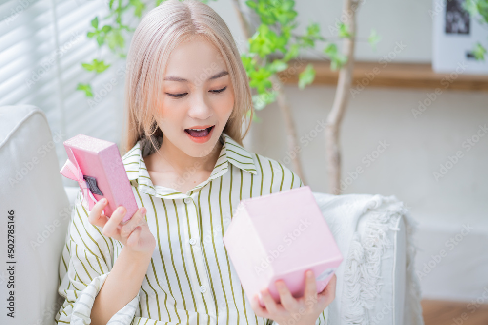 年轻的亚洲女人在家拿着礼盒