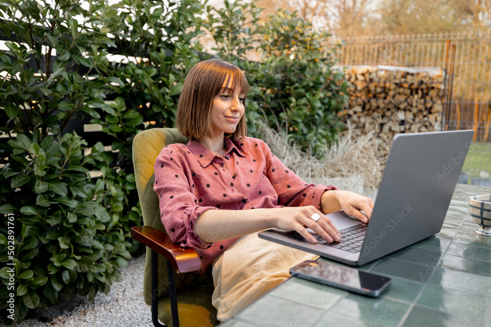 Woman works on laptop online in the garden outdoors