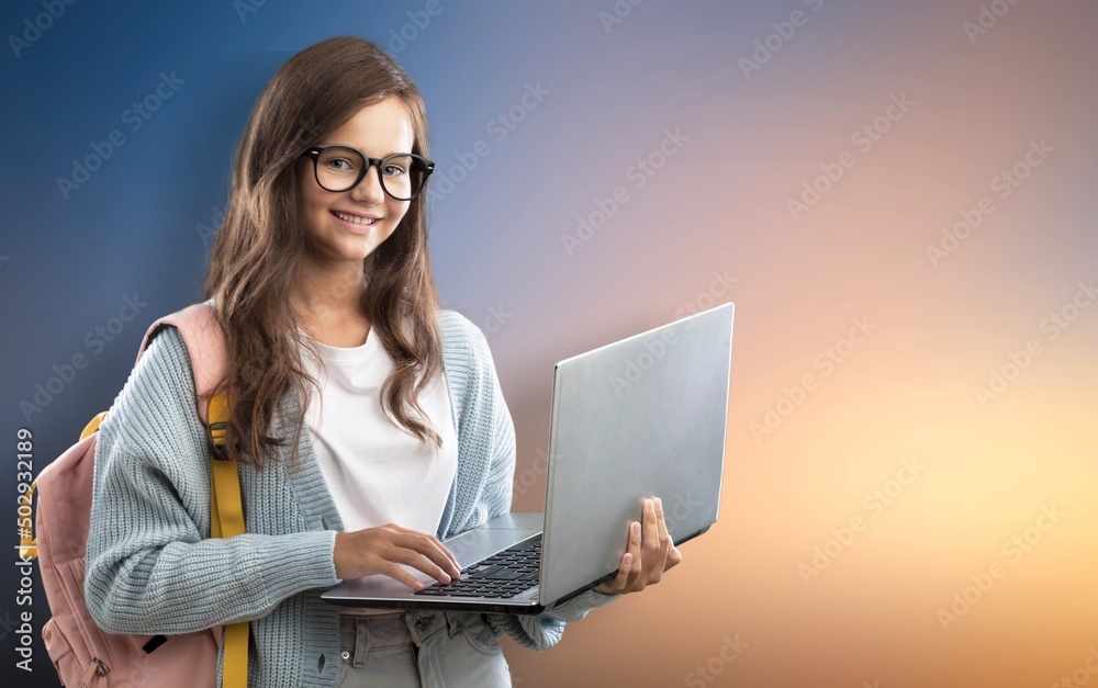 Portrait of smiling teen girl using a laptop computer, studying online