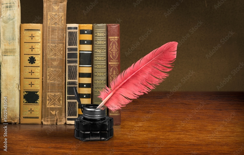 Stack of old  antique books, inkwell with quill pen.