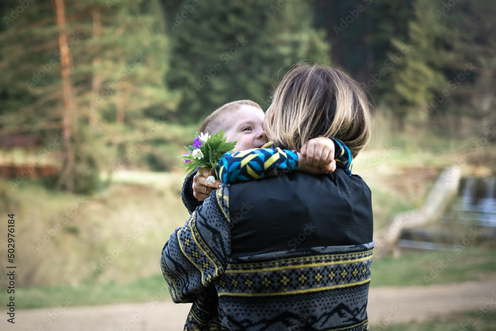 Mom hugs her son after a gift of a bouquet of flowers from him