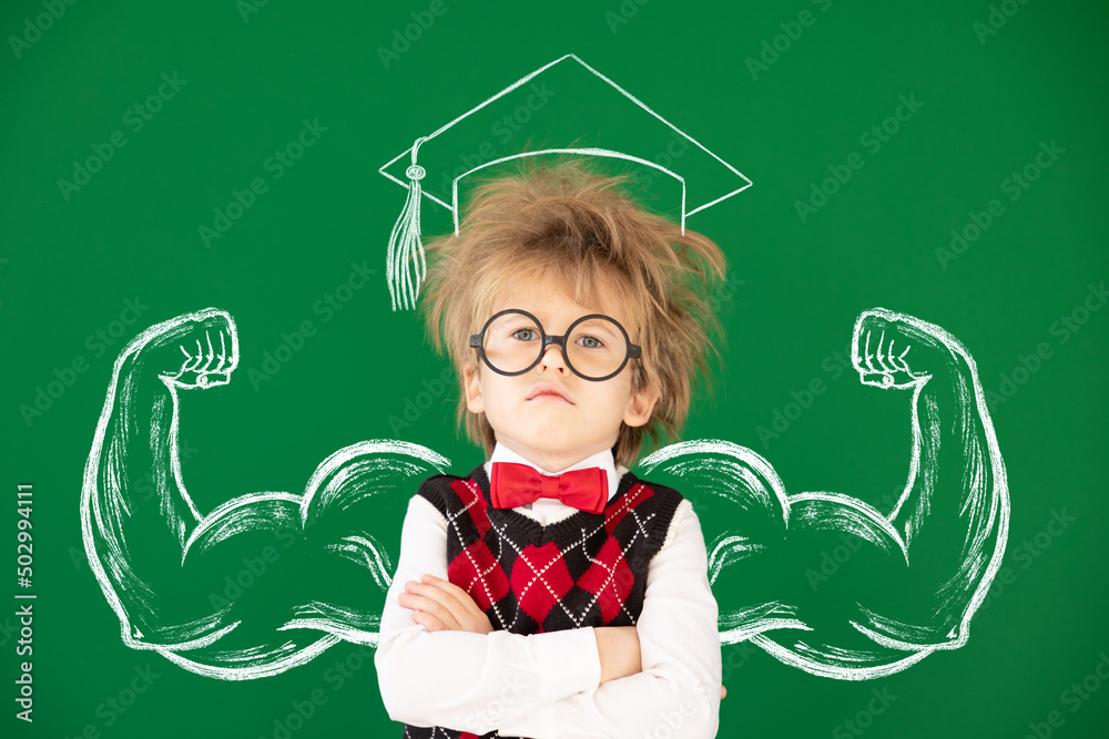 Happy child in class against green chalkboard