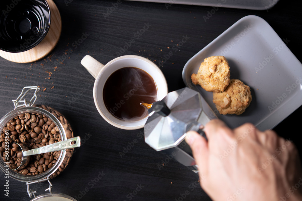 俯视图，咖啡师将咖啡从摩卡壶咖啡机倒入咖啡杯。手持意大利cl