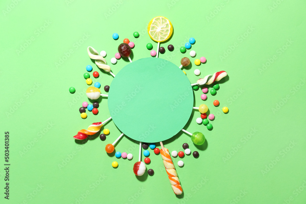 Composition with blank card, lollipops and candies on green background