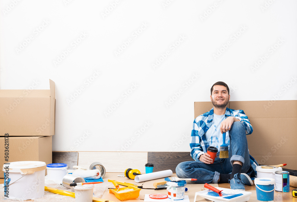 Happy smiling guy relaxing on floor with coffee