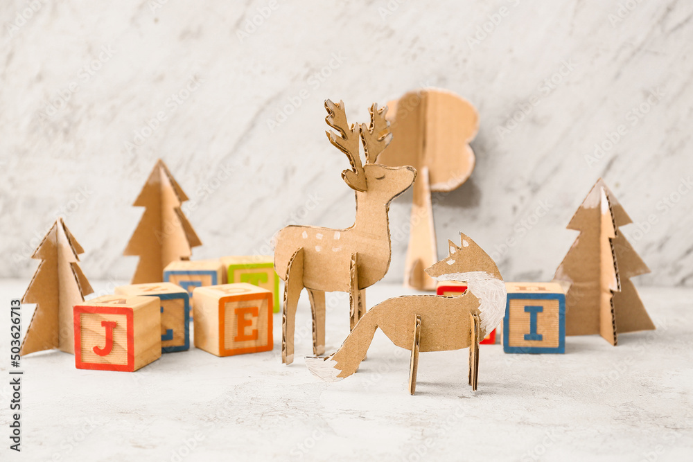 Handmade cardboard toys and wooden cubes with letters on light background