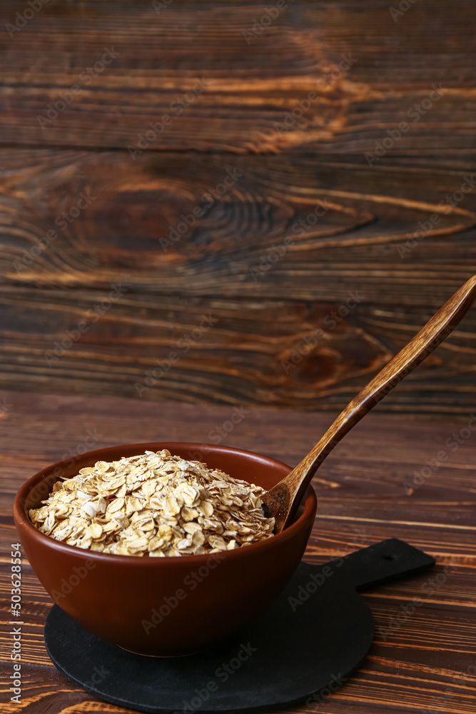 Bowl of raw oatmeal on wooden background