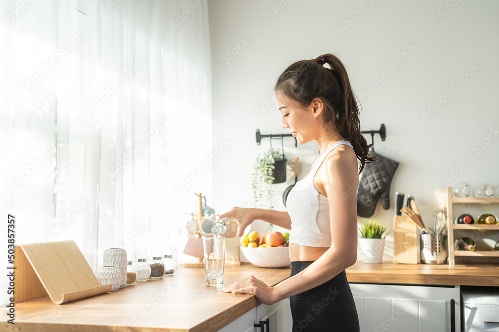 穿着运动服的亚洲美女在家锻炼后喝水