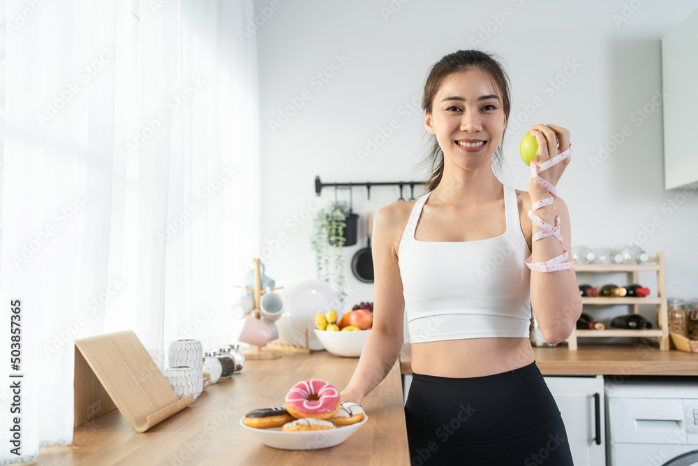 亚洲有魅力的活跃女性在家里的厨房里拿着青苹果。