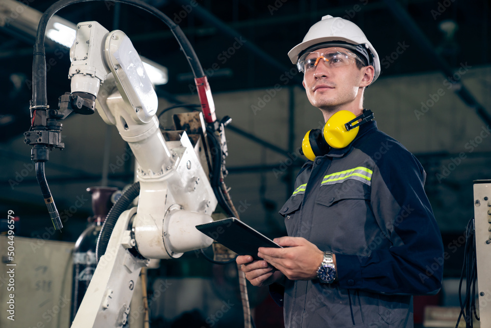 Young factory worker working with adept robotic arm in a workshop . Industry robot programming softw