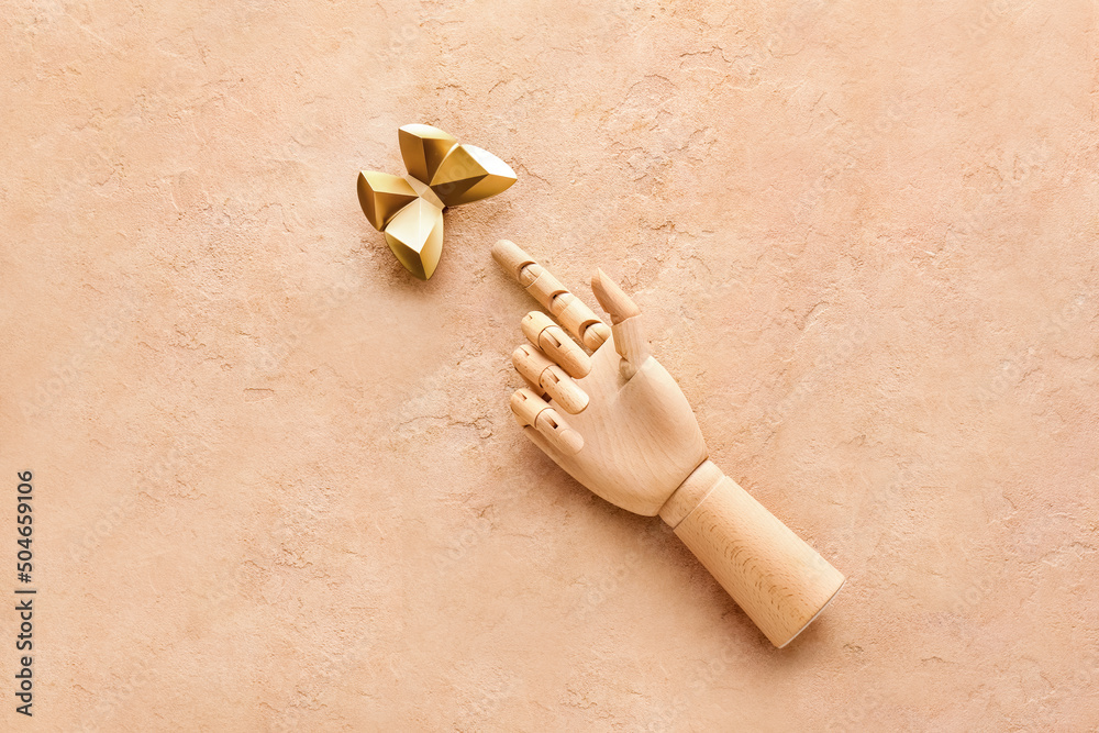 Wooden hand and decor in shape of butterfly on beige background