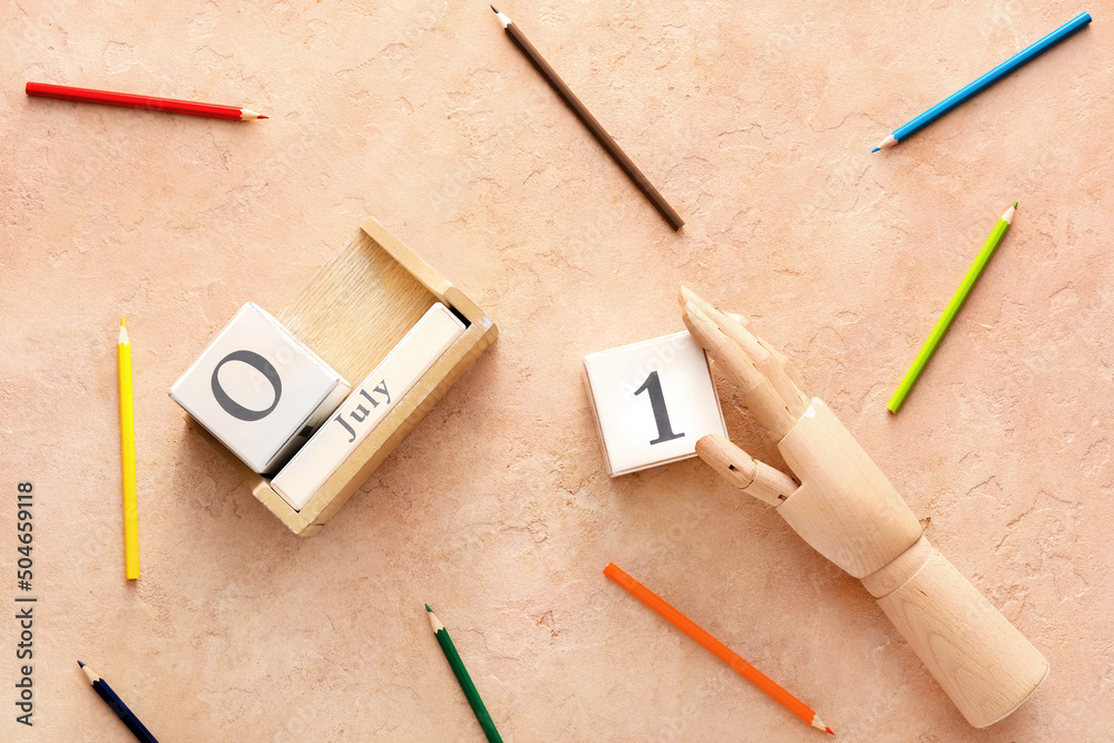 Wooden hand with cube calendar and colorful pencils on beige background