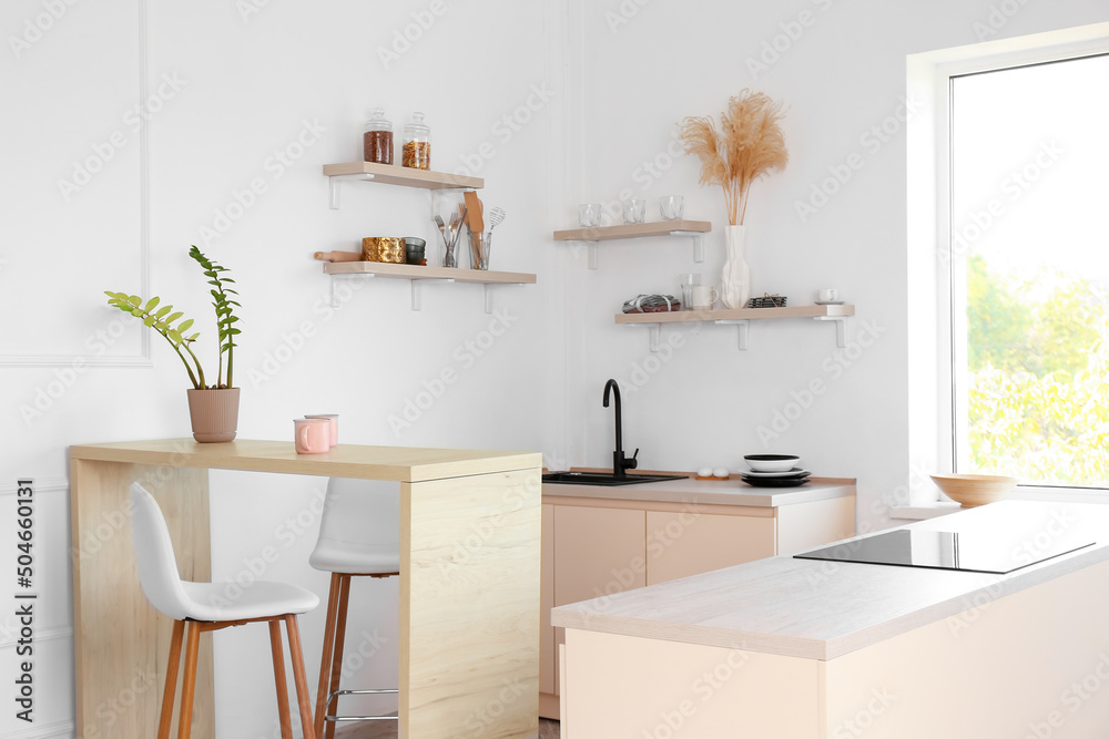 Interior of light kitchen with dining table, sink and electric stove